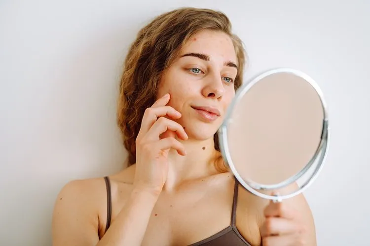 Woman examining skin results from Medik8 skincare